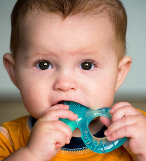A baby boy chewing on a teething ring to alleviate discomfort 