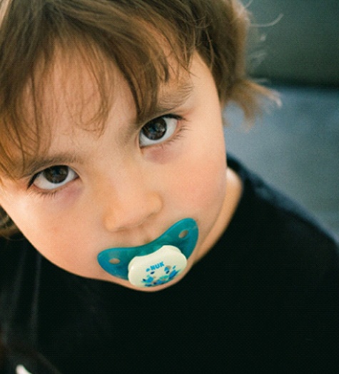An infant looking up and sucking on a pacifier