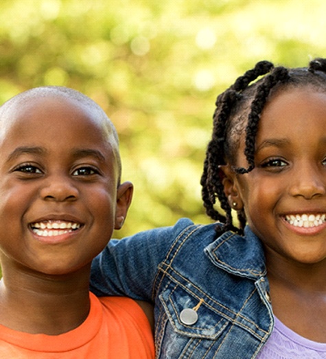 Two young kids smiling and hugging after undergoing pulp therapy