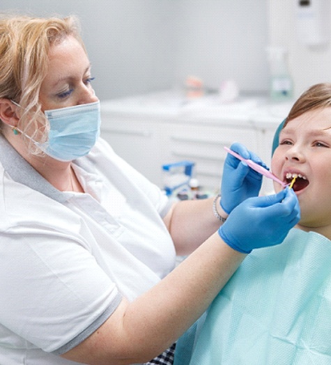 A dental hygienist applies silver diamine fluoride to a young patient during a regular appointment