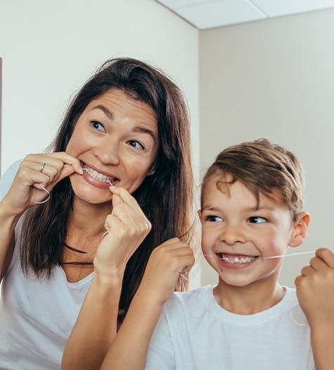 Mother and son flossing to prevent children’s toothache in Garland