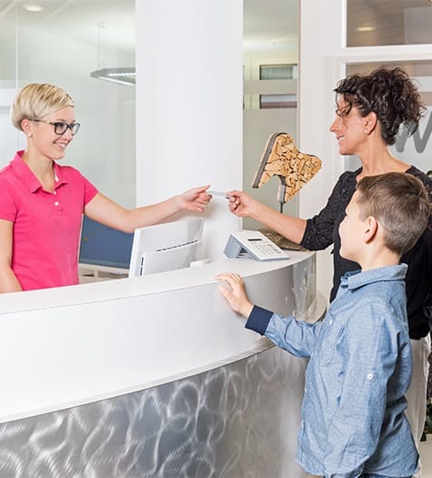 Family and receptionist discussing the cost of kids emergency dental care in Garland