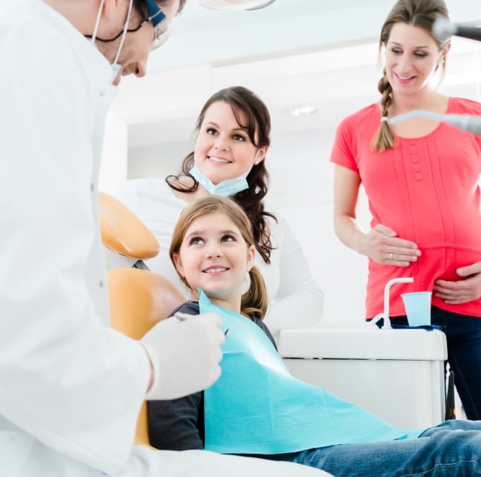 Dentist and dental team member talking to child during pediatric dental checkup