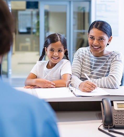 Mother and daughter completing forms at dental office