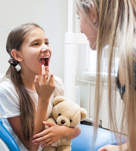 Child pointing to smile after dental sealant application