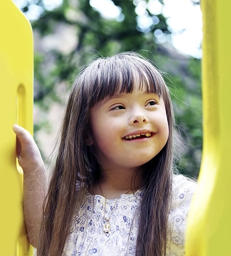 Smiling little girl on playground with missing front tooth