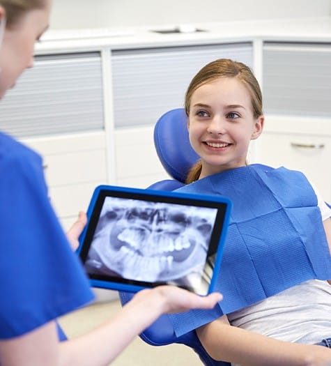 Dentist showing child digital x-rays on tablet computer