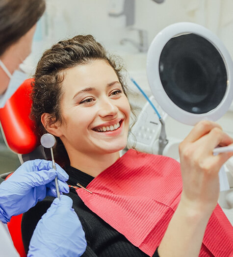 A teenage girl looking at her smile in the mirror after a dental checkup