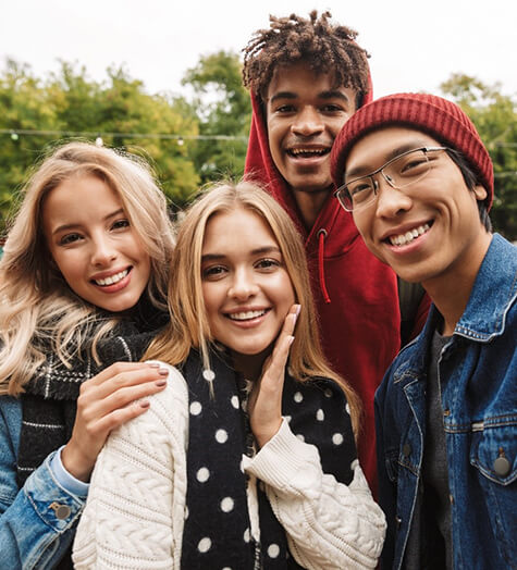 A group of male and female teenagers smiling after having their teeth whitened