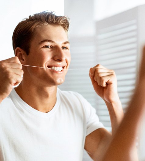 A teenager flossing his teeth