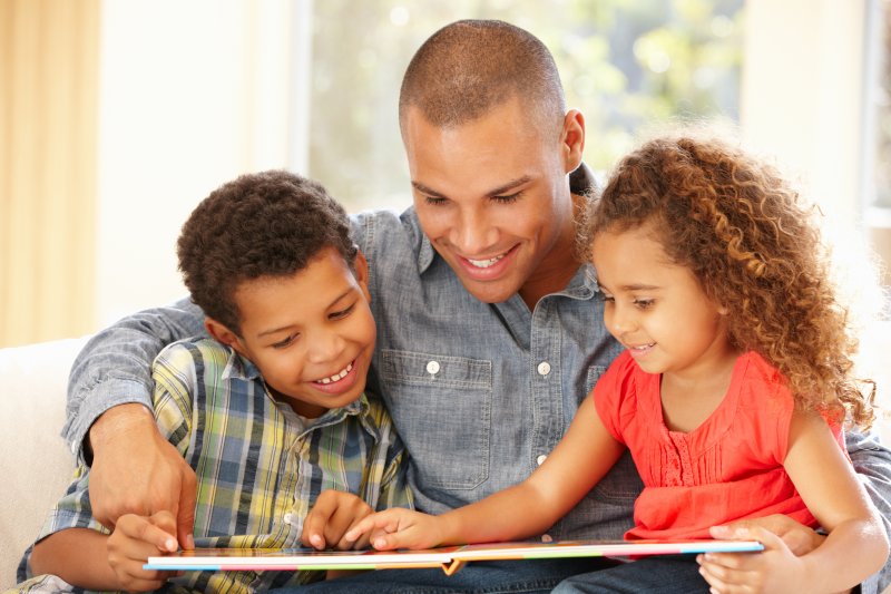 a father reading to his two children about visiting the dentist