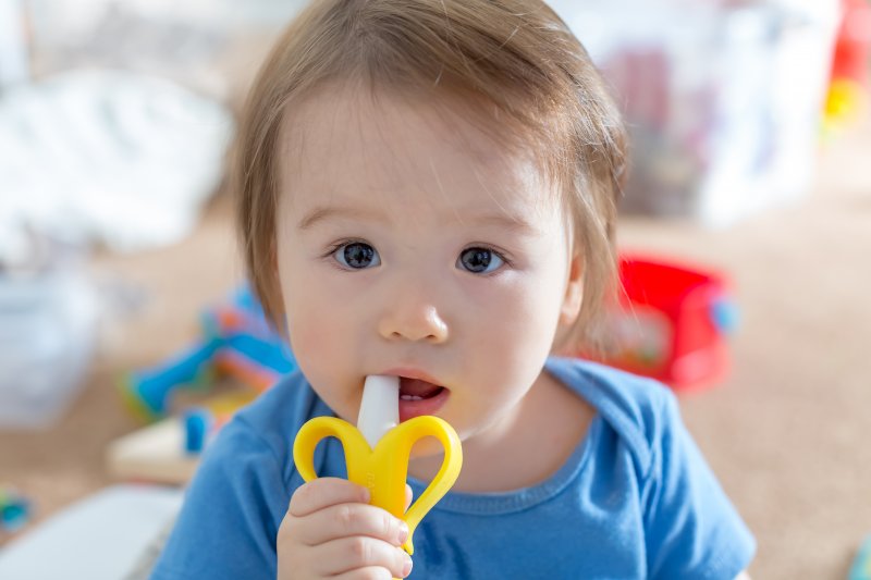 a baby chewing on a plastic teether because it is teething in Garland