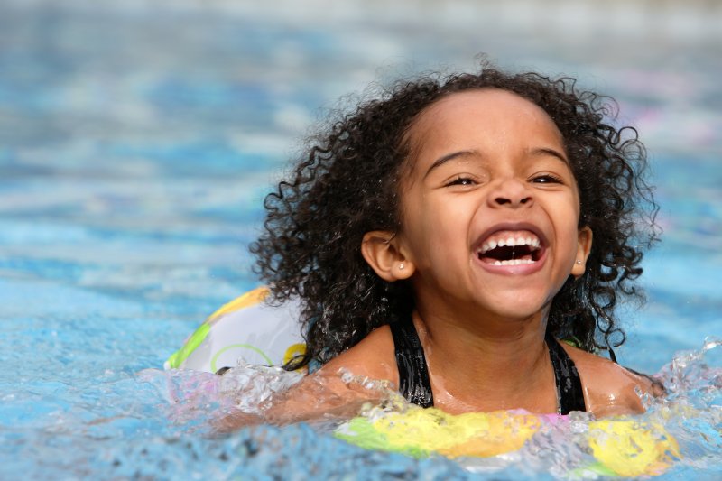 a little girl laughing and swimming while on summer vacation in Garland