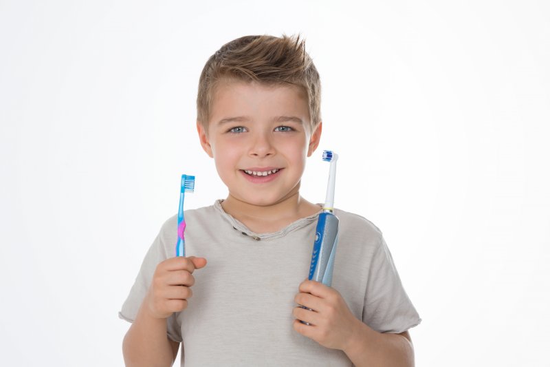 young boy using an electric toothbrush
