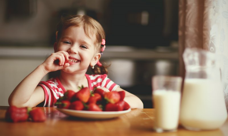 girl eating bowl of strawberries