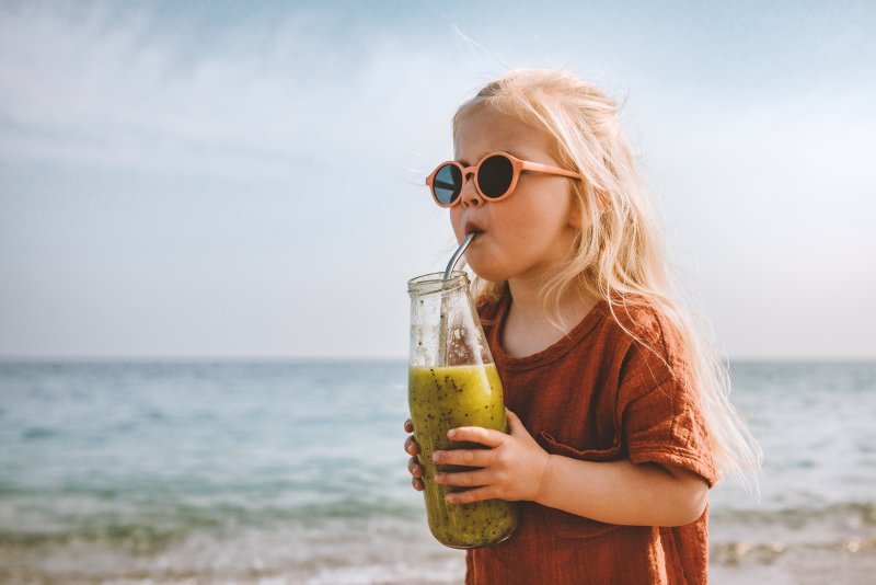 Portrait of a child with some dope sunglasses drinking juice
