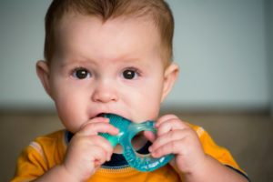 a baby chewing on a teething ring 