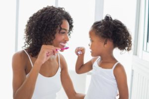 a mother brushing teeth with her child