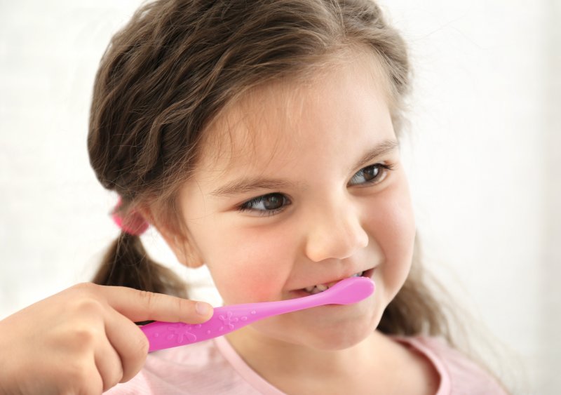 child brushing teeth with fluoride toothpaste