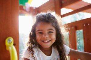 girl with baby teeth smiling at a park