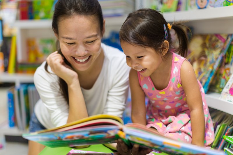 Child reading a dental anxiety book with her mother