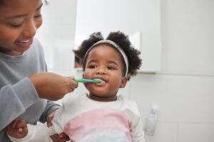 Mom brushing toddler's teeth. 