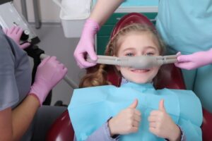 little girl holding her thumbs up as she gets nitrous oxide sedation