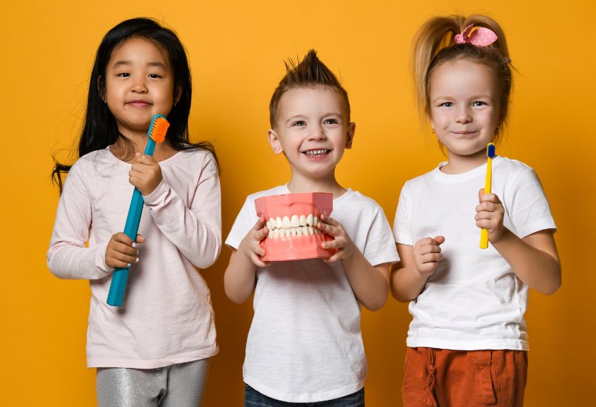Children holding giant toothbrushes and dentures