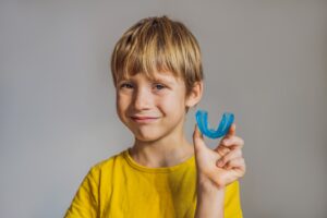Young boy holding up mouthguard.